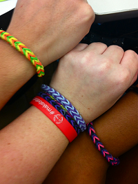 Two students and their corps member model their new bracelets. 